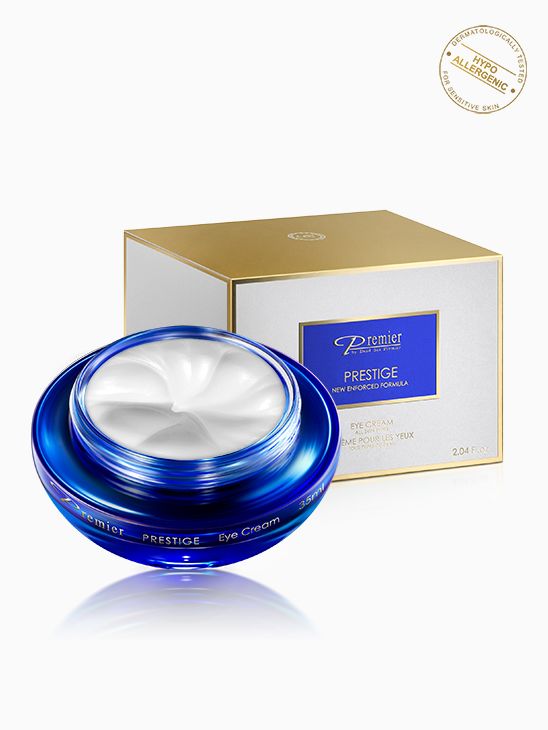 Crema para el contorno de ojos Premier Prestige de 60 ml en tarro azul abierto con caja blanca y dorada.