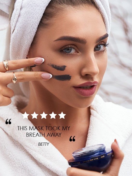 Modelo aplicando mascarilla Milagro Negro de Premier en la mejilla y sosteniendo el tarro azul, con reseña superpuesta.